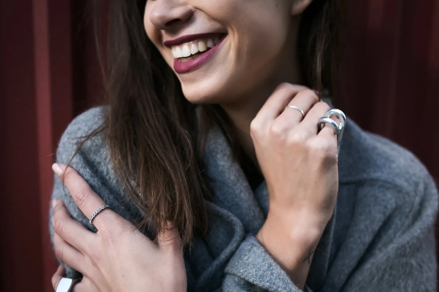 A smiling woman wearing stainless steel rings, showcasing the understated elegance of minimalist jewelry