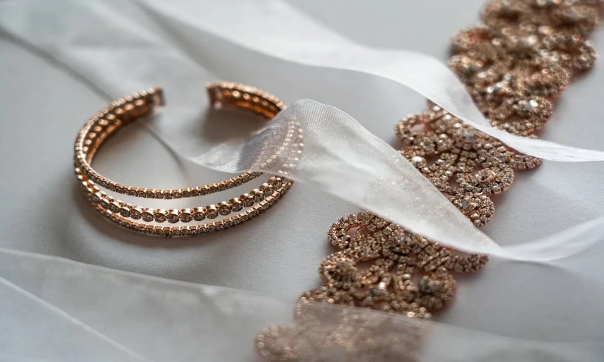 Close up of sparkling rose gold earring and necklace pieces with a sheer ribbon Close up of sparkling rose gold earring and necklace pieces with a sheer ribbon