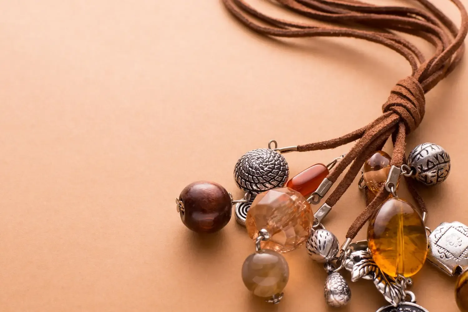 Various beads and charms on leather strands against a tan backdrop Various beads and charms on leather strands against a tan backdrop