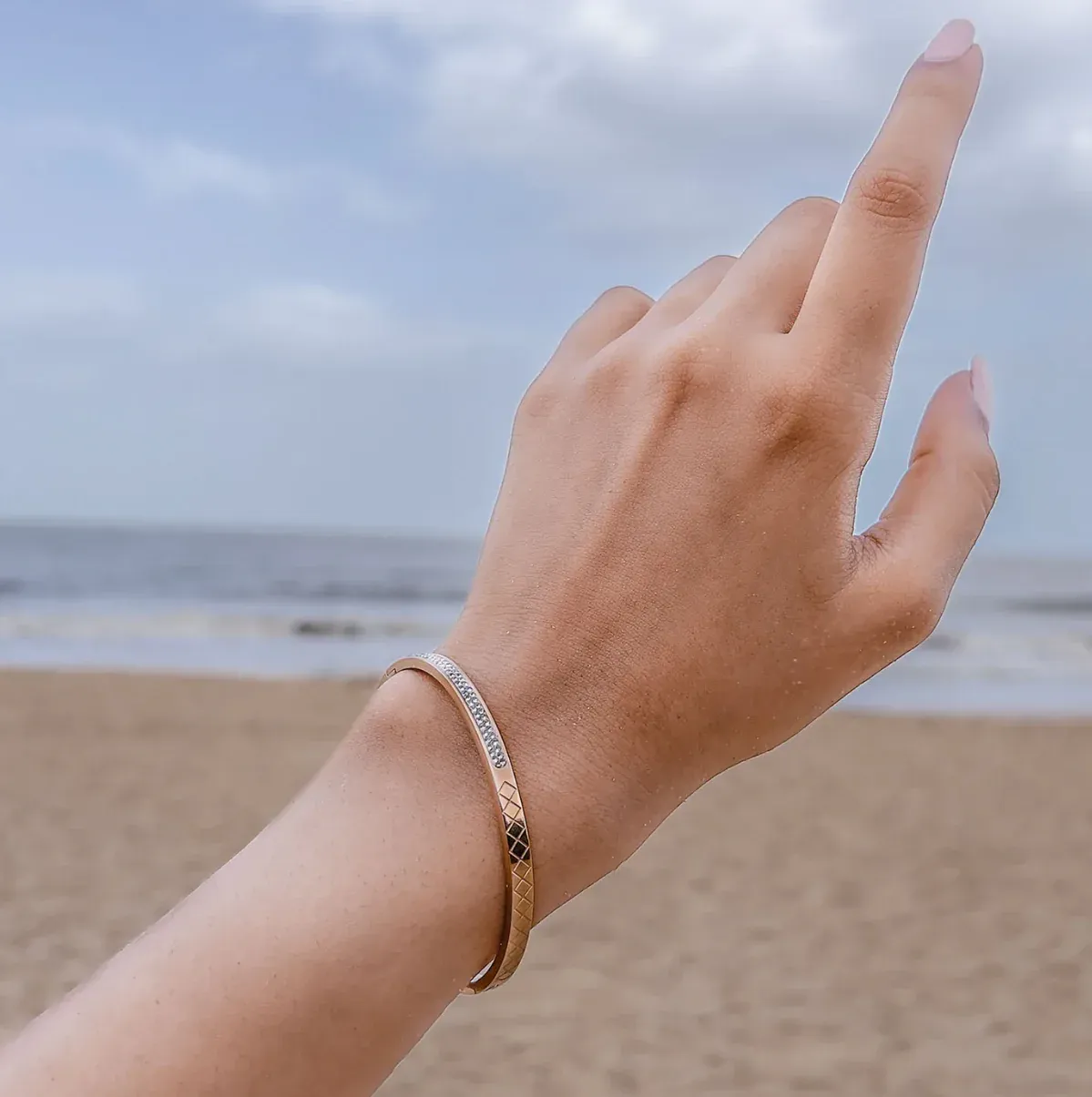 A hand wearing a slim gold and silver bracelet A hand wearing a slim gold and silver bracelet
