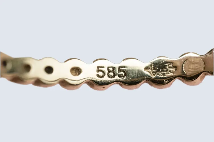 Close up of a gold piece marked with 585 and additional hallmarks Close up of a gold piece marked with 585 and additional hallmarks