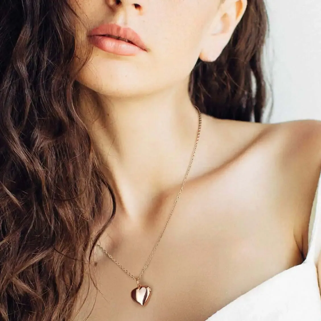 Close up of a woman wearing a gold necklace with a rose gold heart pendant Close up of a woman wearing a gold necklace with a rose gold heart pendant