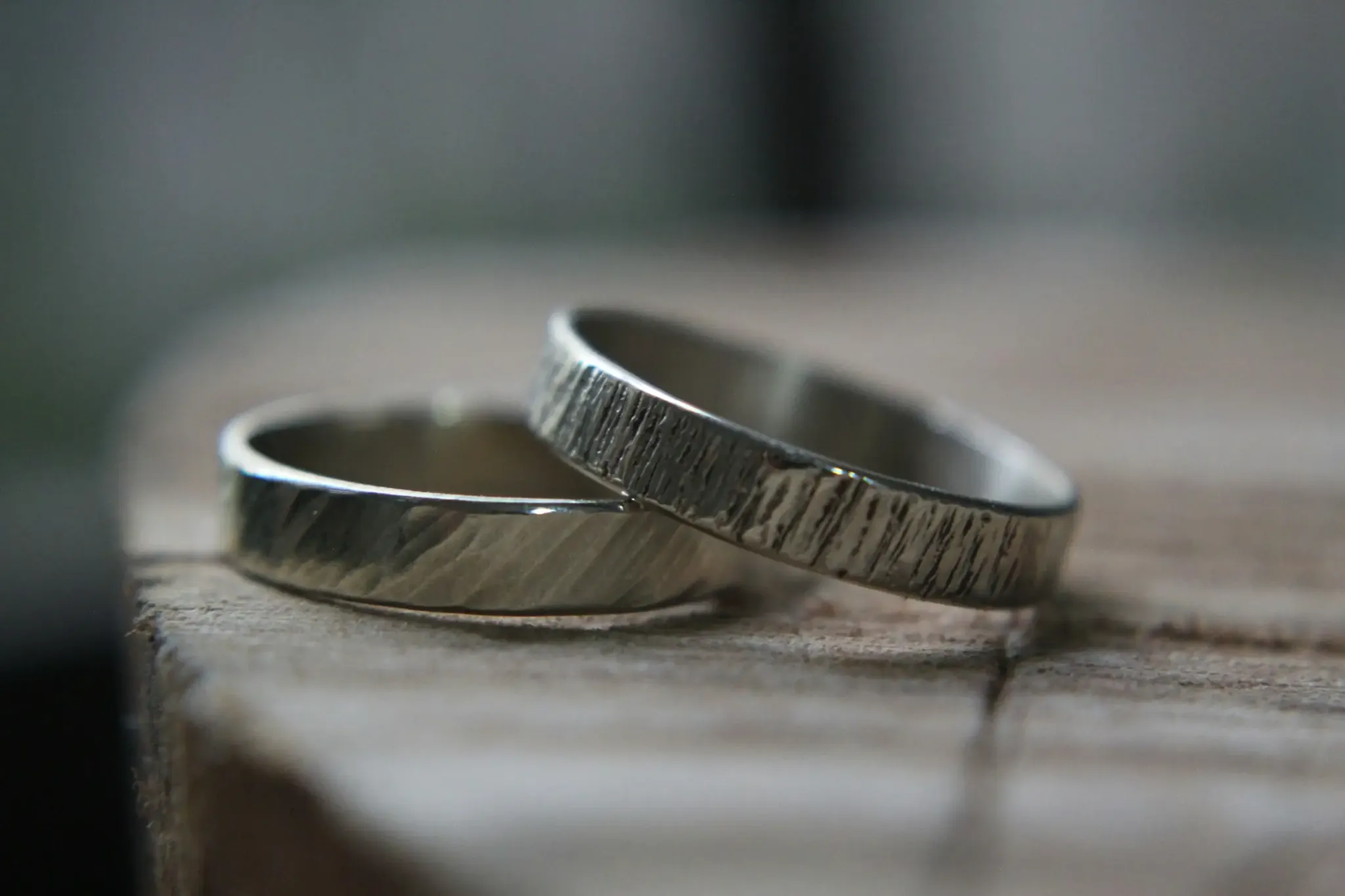 Two rings with textured designs placed on a wooden surface Two rings with textured designs placed on a wooden surface