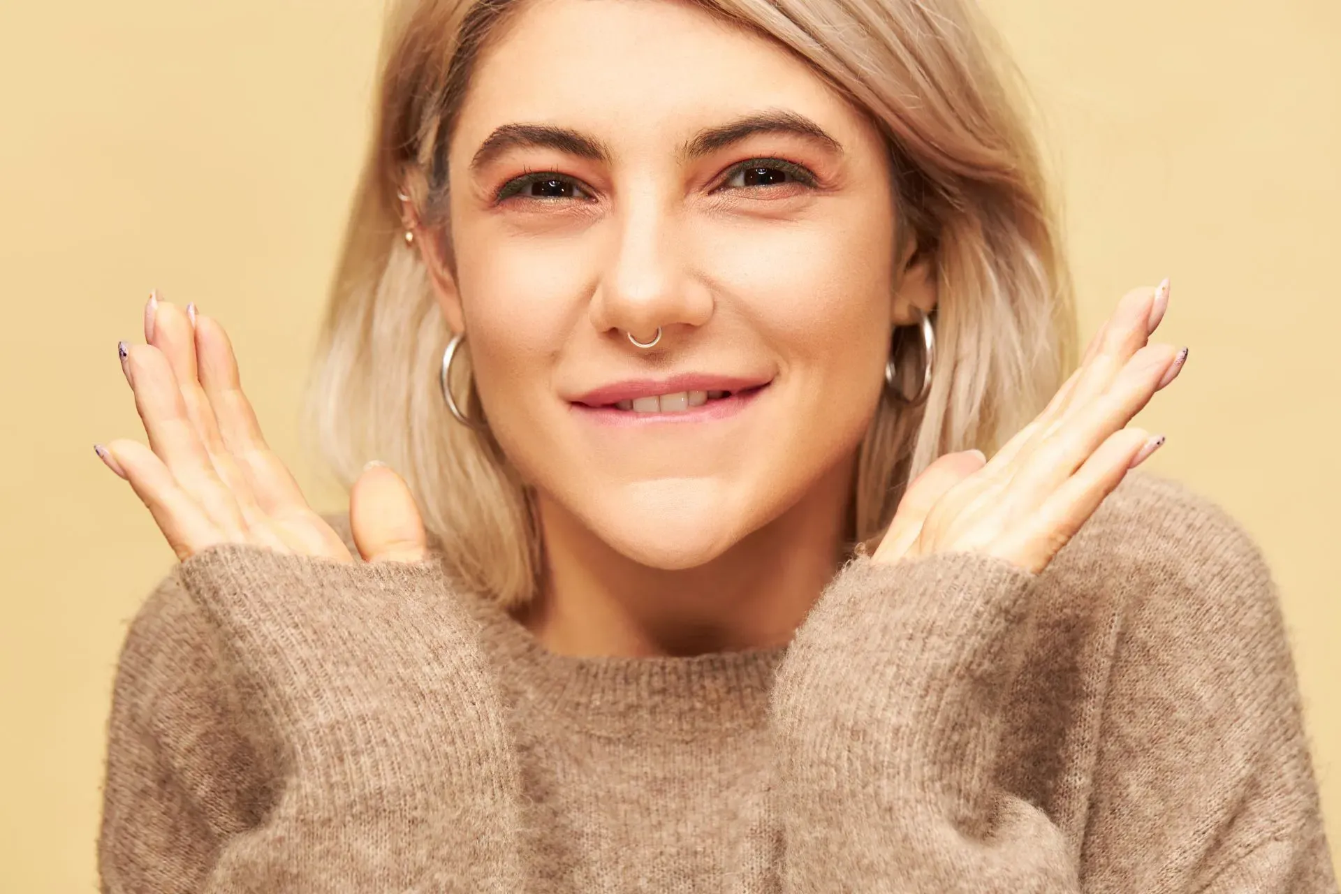 a smiling young woman with a nose ring and hoop earrings