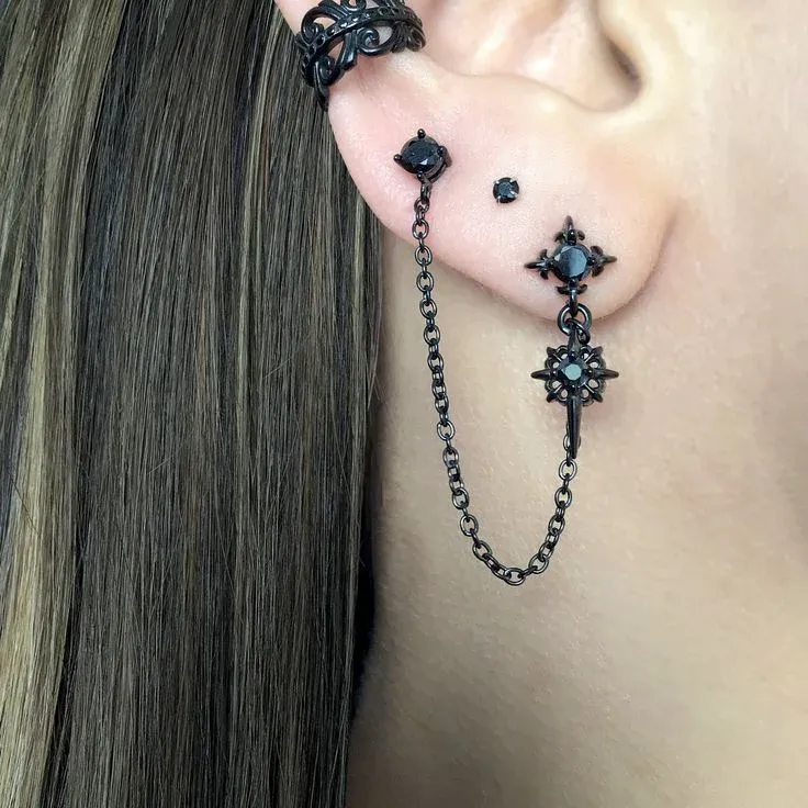 close up of a woman's ear adorned with multiple black earrings close up of a woman's ear adorned with multiple black earrings