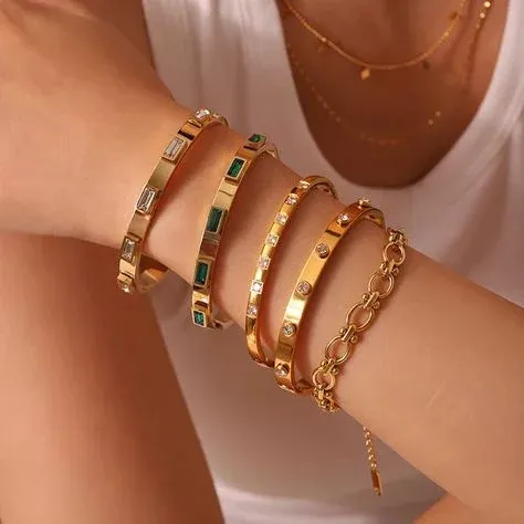 Arm adorned with several gold bracelets featuring various gemstones Arm adorned with several gold bracelets featuring various gemstones