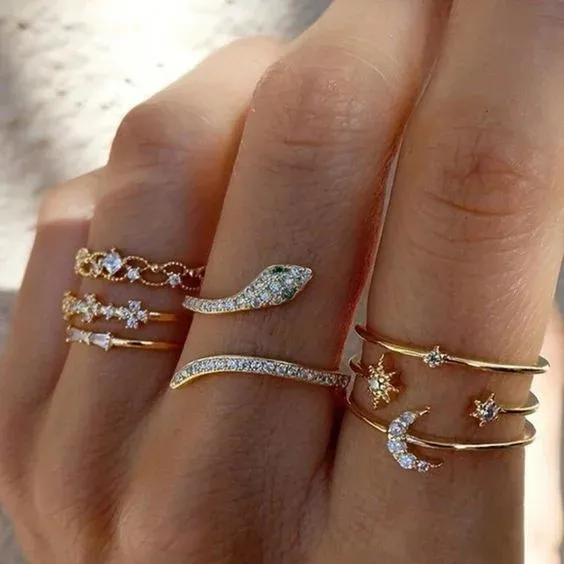 Fingers adorned with multiple gold rings featuring various designs Fingers adorned with multiple gold rings featuring various designs