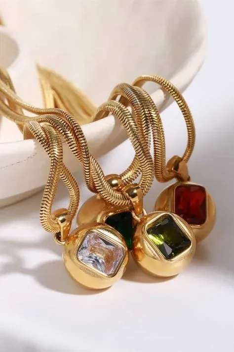 Gold necklaces with colorful gemstone pendants displayed on a dish Gold necklaces with colorful gemstone pendants displayed on a dish