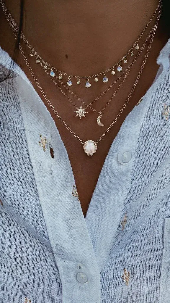 Layered gold necklaces with pendants on a white shirt Layered gold necklaces with pendants on a white shirt