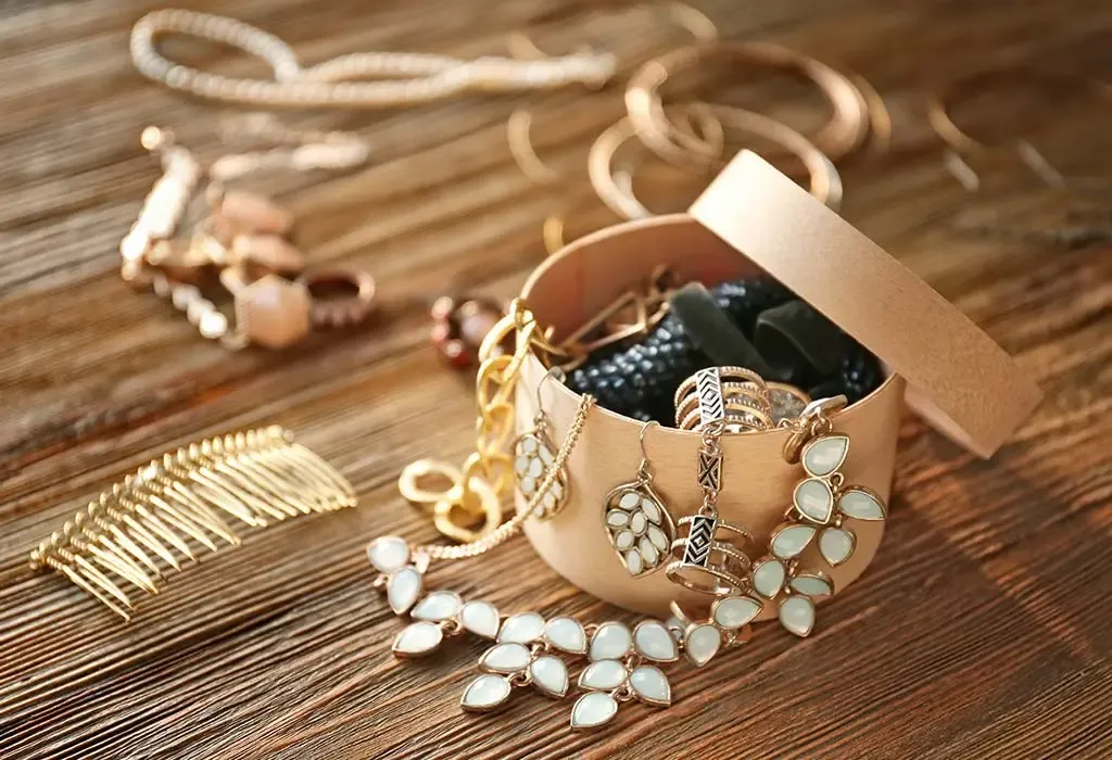 Open jewelry box with assorted gold and gemstone pieces on a wooden surface Open jewelry box with assorted gold and gemstone pieces on a wooden surface