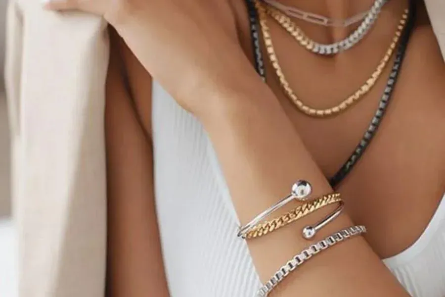 Woman wearing layered gold and silver necklaces and bracelets Woman wearing layered gold and silver necklaces and bracelets