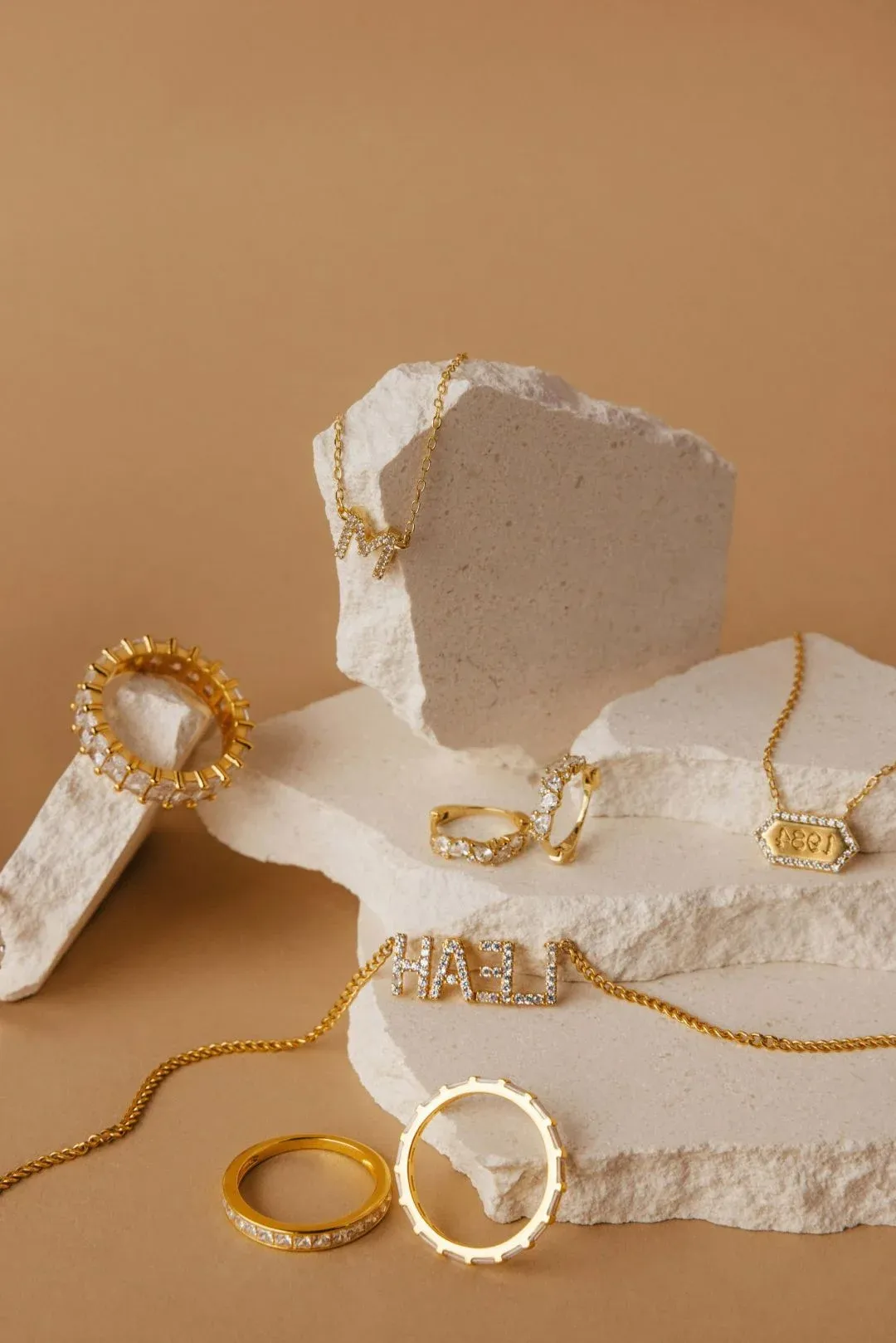 Assorted gold jewelry pieces displayed on beige stones Assorted gold jewelry pieces displayed on beige stones
