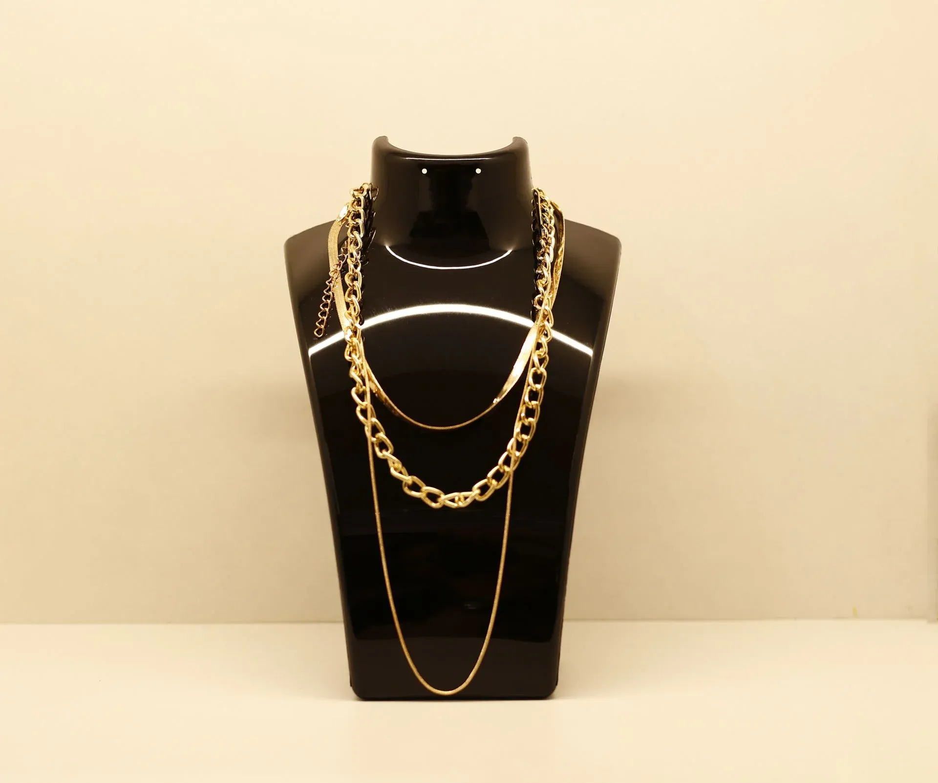 Gold chains displayed on a black jewelry bust Gold chains displayed on a black jewelry bust