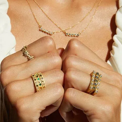 Hands with gold rings and necklace against white blouse Hands with gold rings and necklace against white blouse