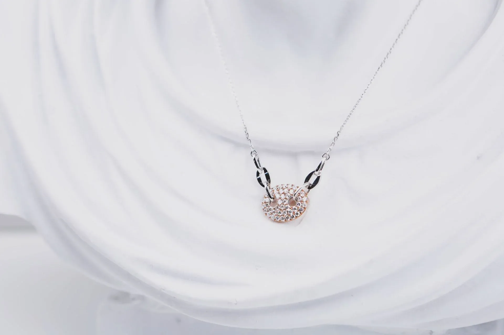Silver necklace with diamond pendant on a white bust