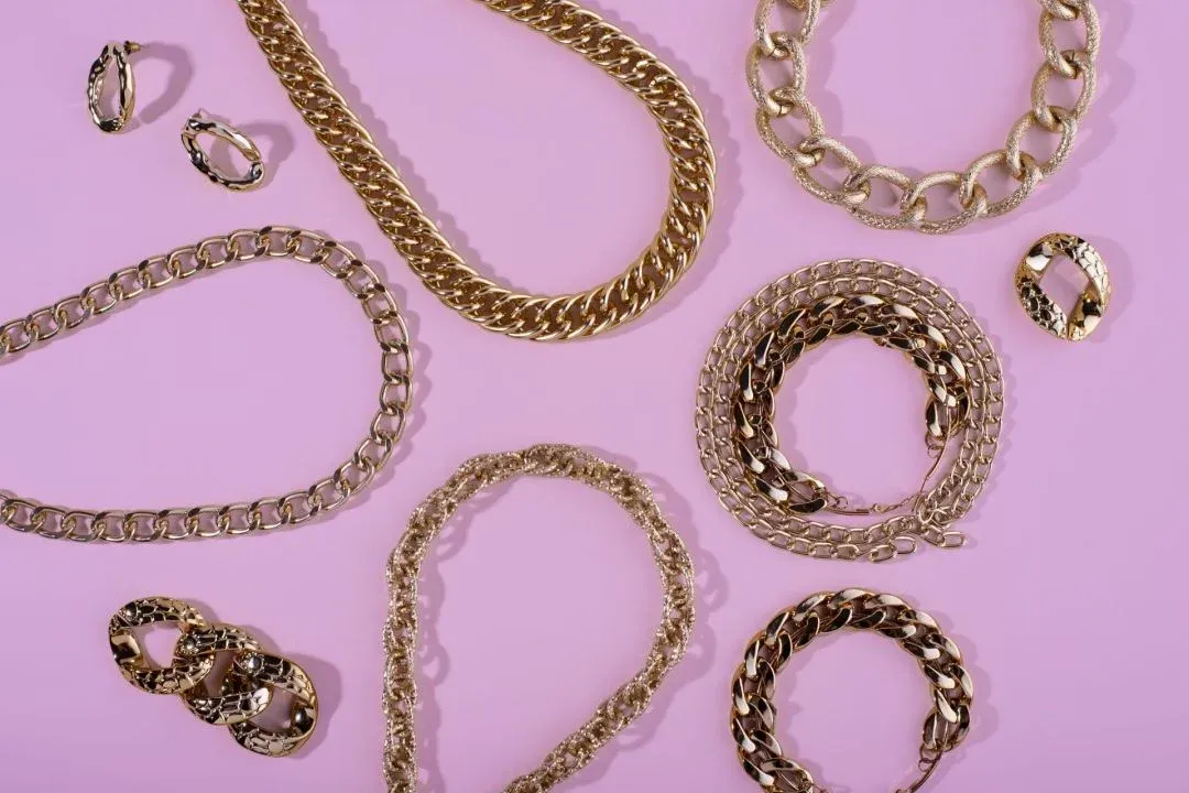 Various gold chains and rings laid out on a pink background Various gold chains and rings laid out on a pink background