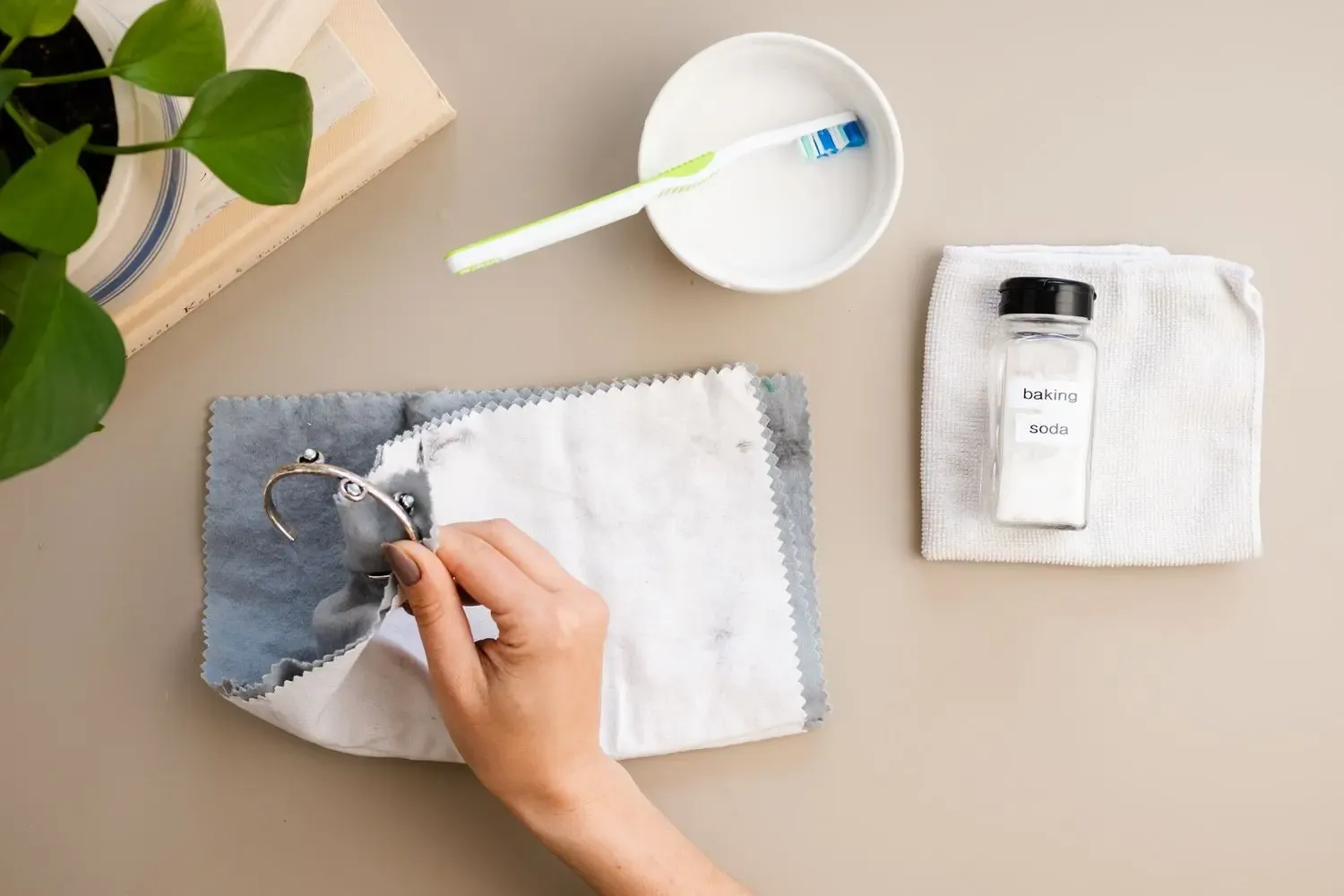 Hand cleaning a bracelet with a cloth, baking soda nearby Hand cleaning a bracelet with a cloth, baking soda nearby