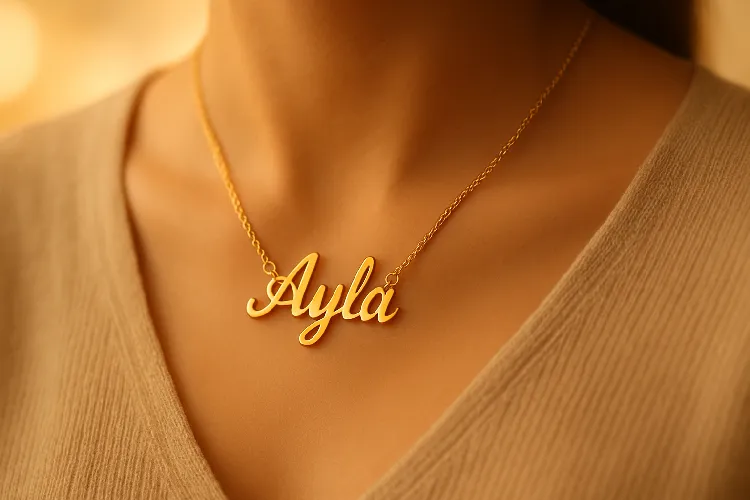 Custom gold name necklace worn by a person against a glowing background. Custom gold name necklace worn by a person against a glowing background.