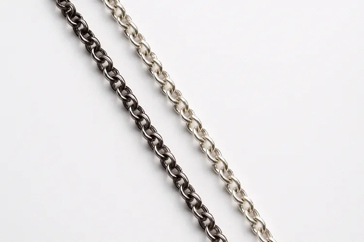 Overhead shot of stainless steel and sterling silver rolo chains on a white surface Overhead shot of stainless steel and sterling silver rolo chains on a white surface