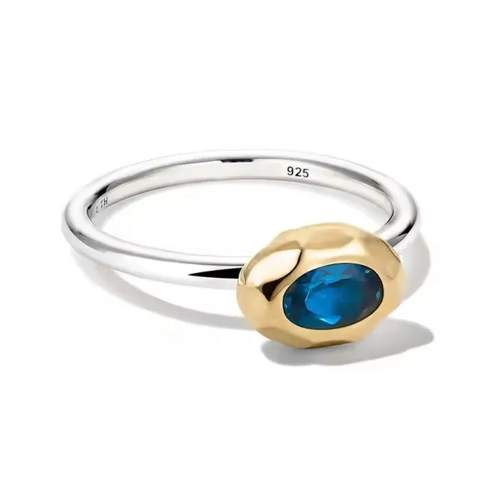 Silver band with a gold bezel and blue oval gemstone