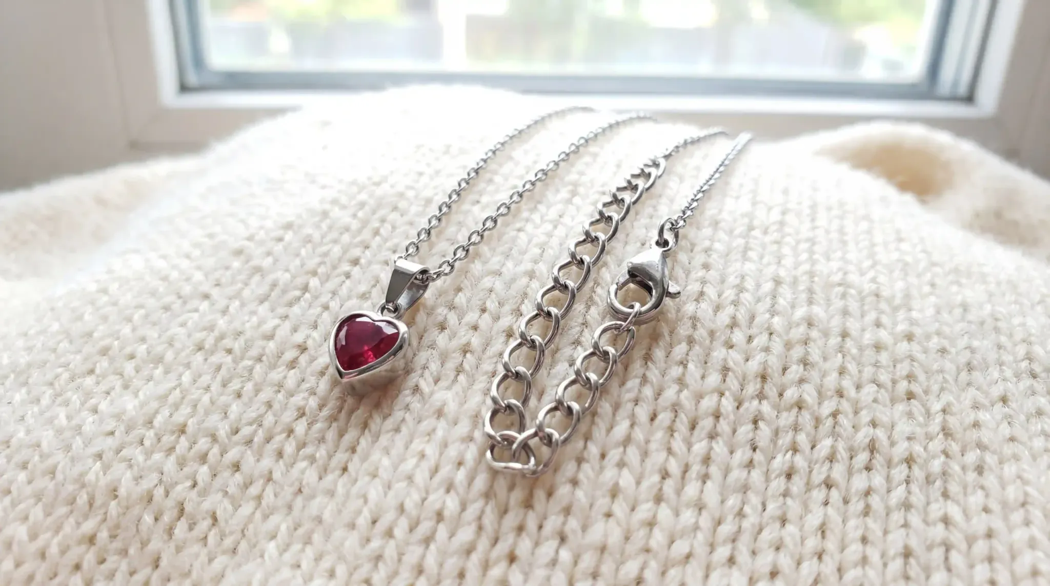 A delicate child birthstone heart necklace featuring a vibrant red stone and a durable stainless steel chain