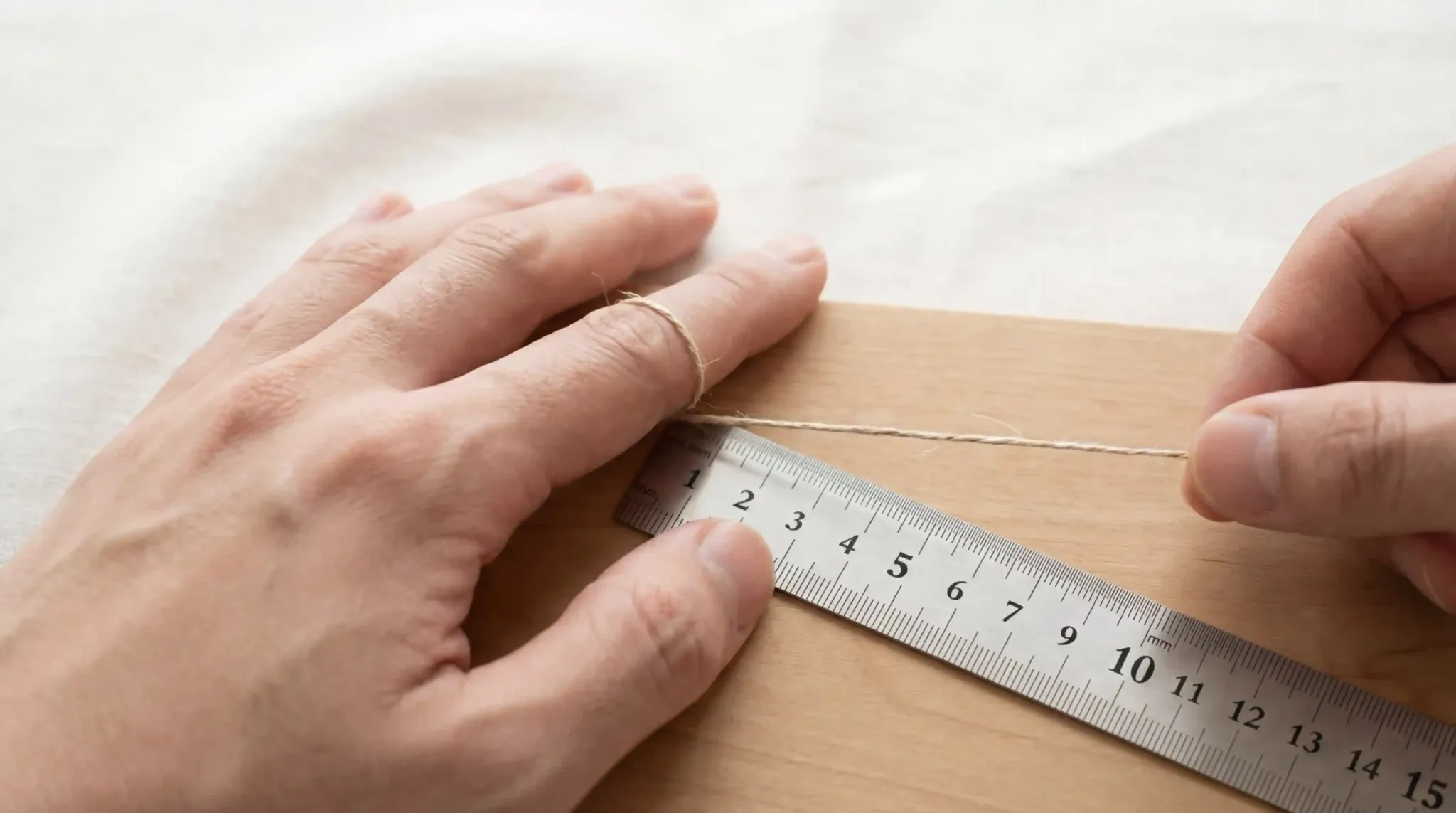 A close-up photo showing a hand being measured with a paper strip and a ruler to find the perfect ring size.