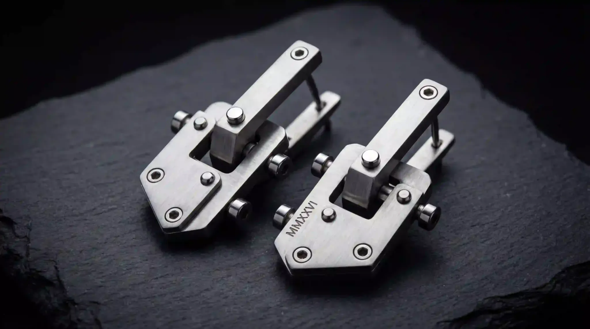 Industrial grade 316L stainless steel earrings featuring a rugged, matte architectural design on a slate background.