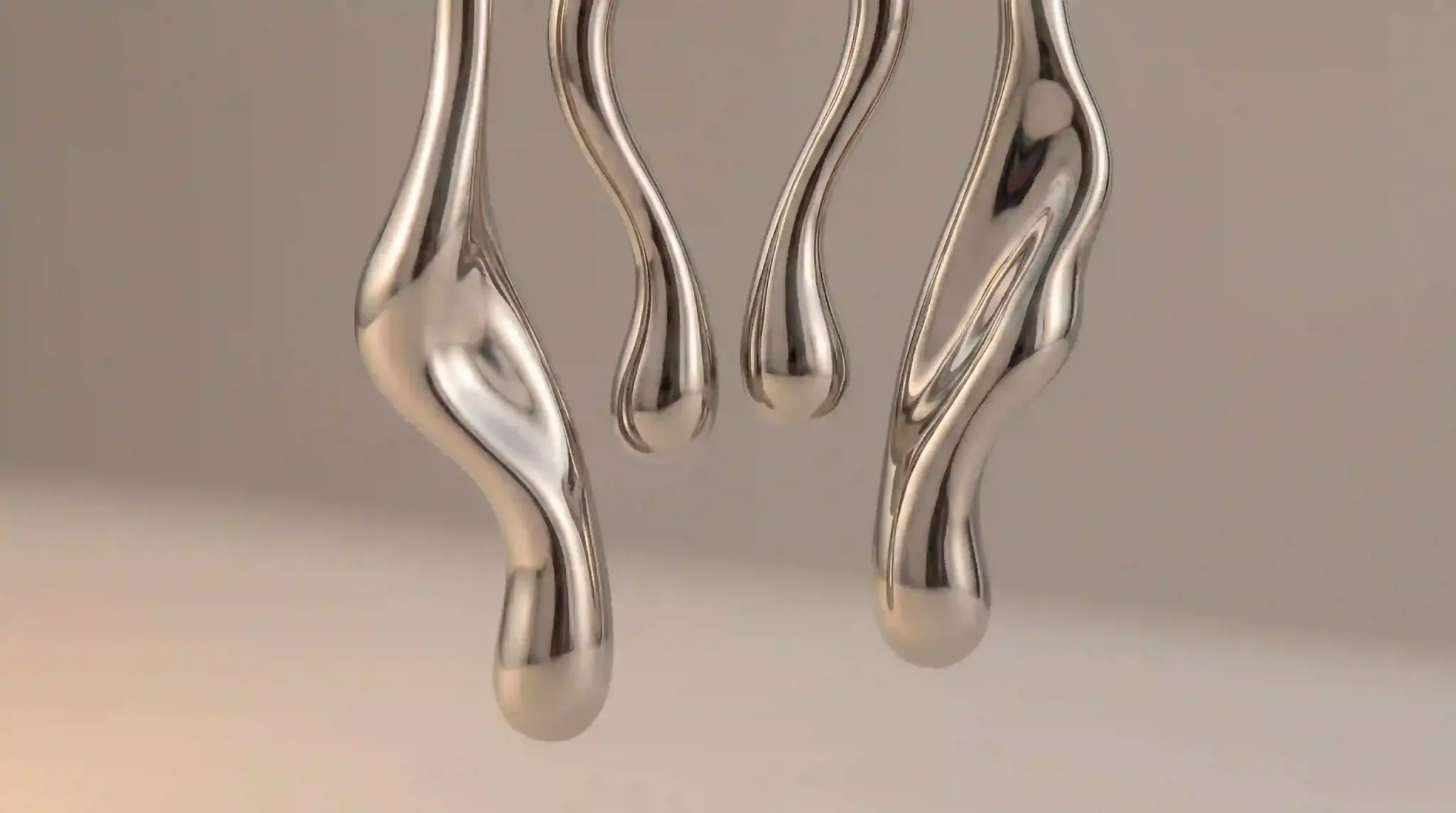 A set of fluid, organic liquid metal earrings appearing to drip downward in a mirror-like silver finish.