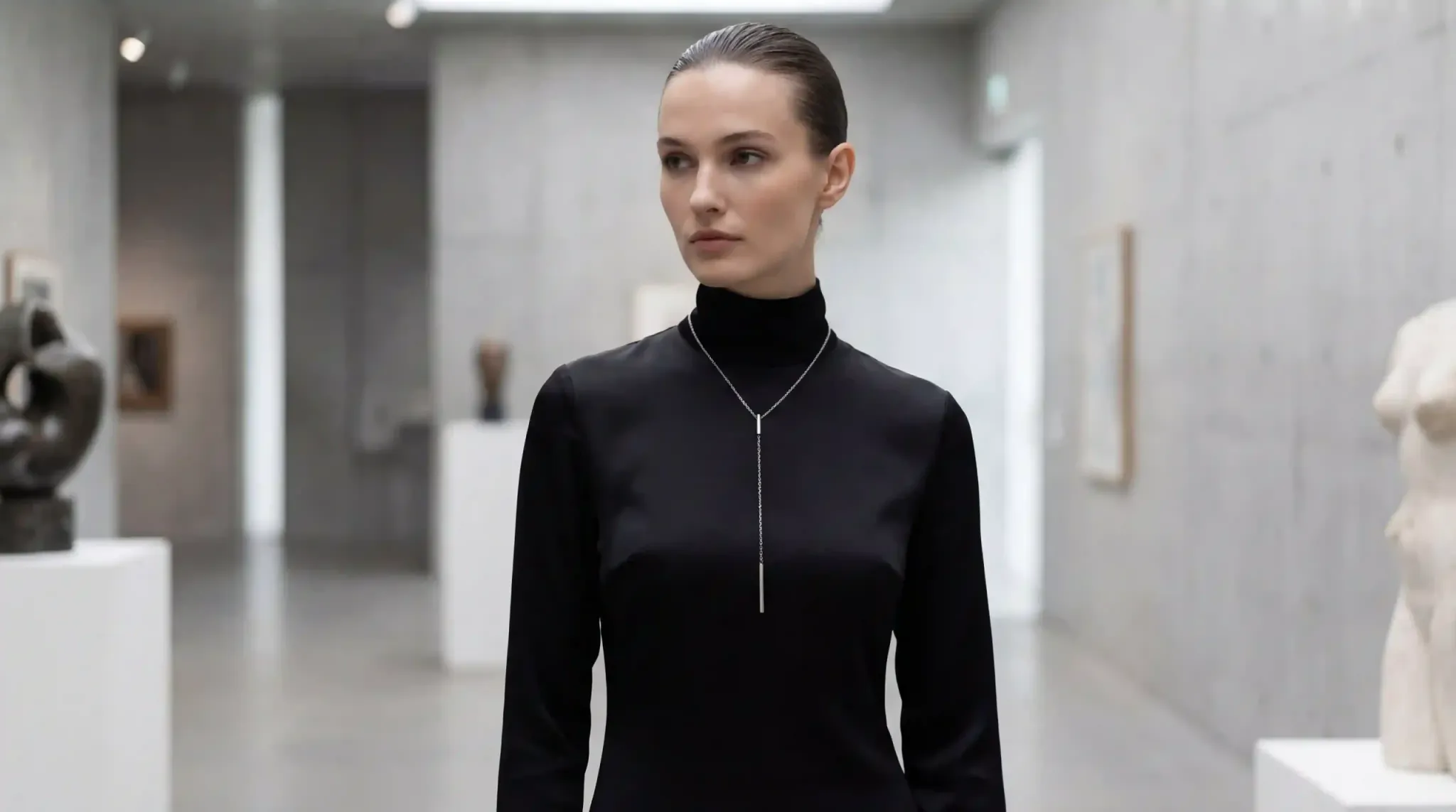 Minimalist fashion portrait featuring a long 316L stainless steel lariat necklace over a black turtleneck, showcasing how vertical lines elongate the torso.