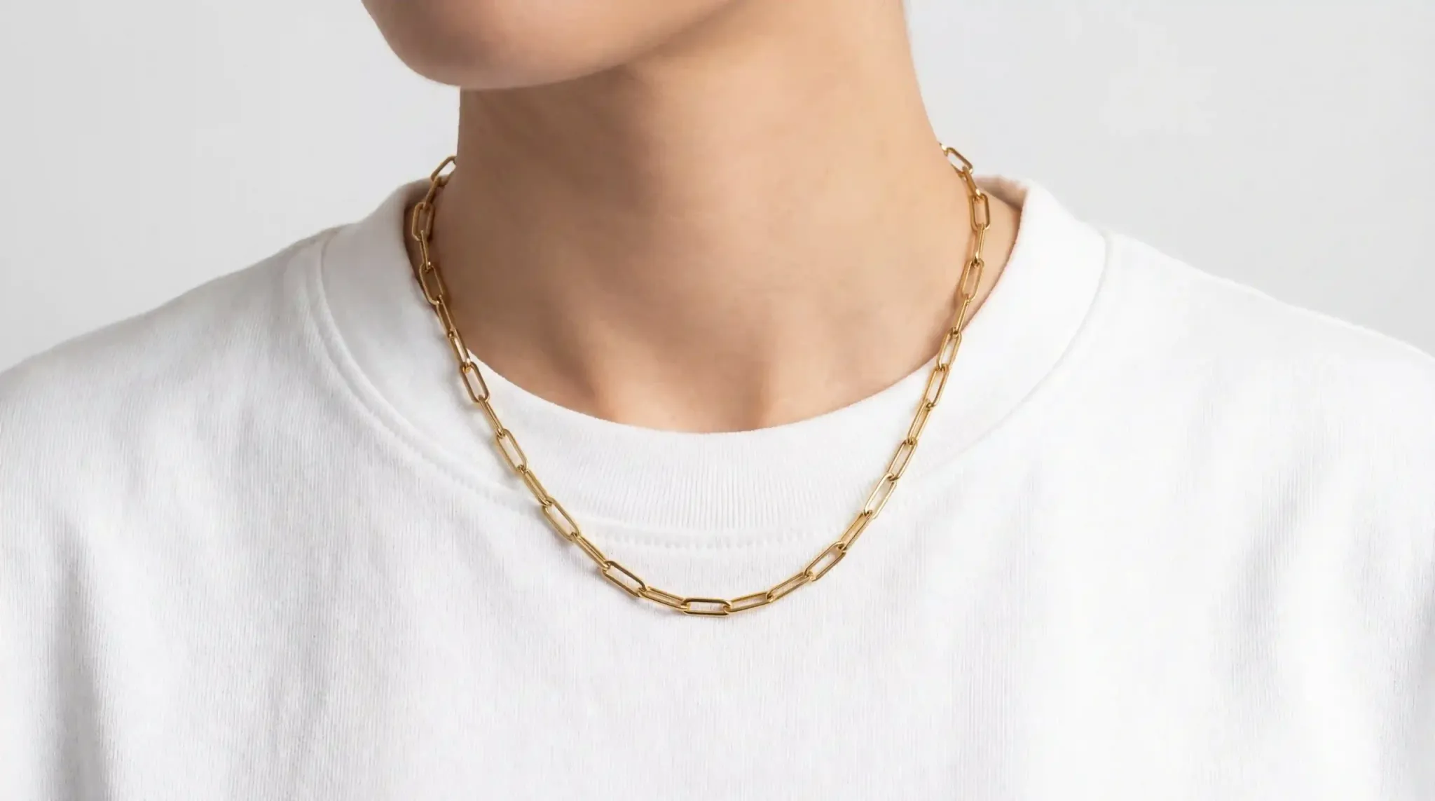 Gold paperclip chain resting on a white crew-neck shirt