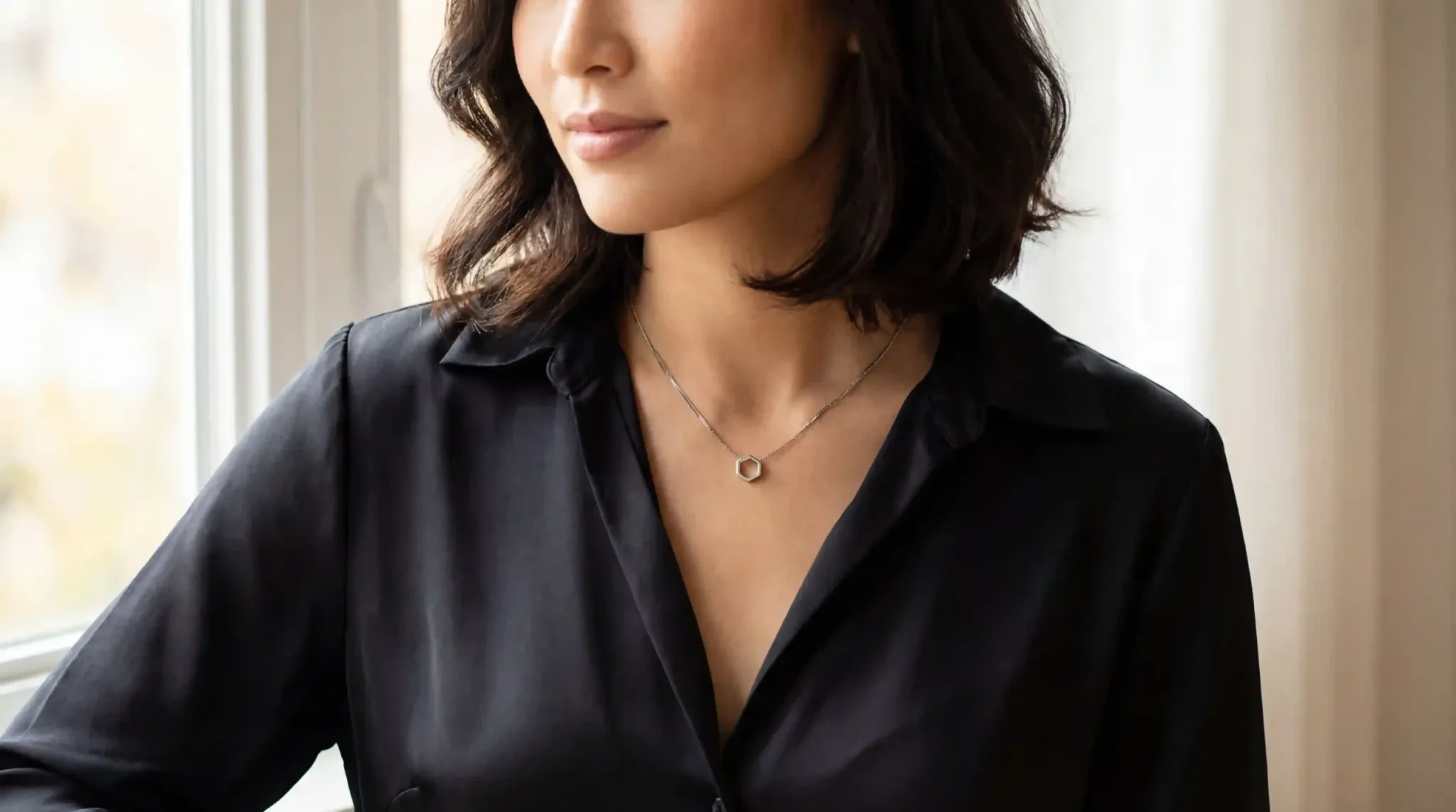 Dainty pendant hanging in a V-neck silk blouse