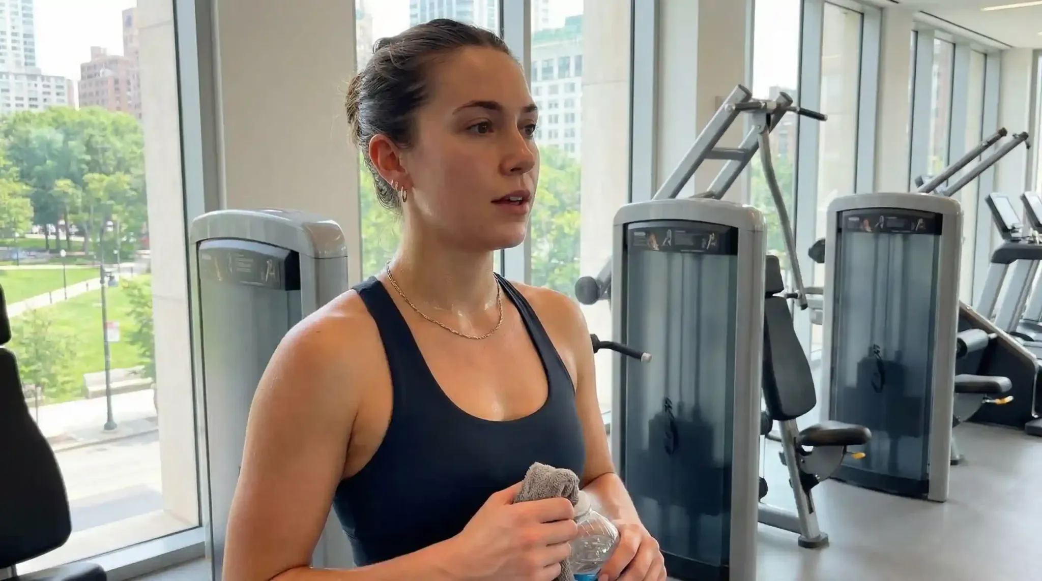 A woman wearing a stainless steel necklace and earrings during a workout to show sweat resistance.