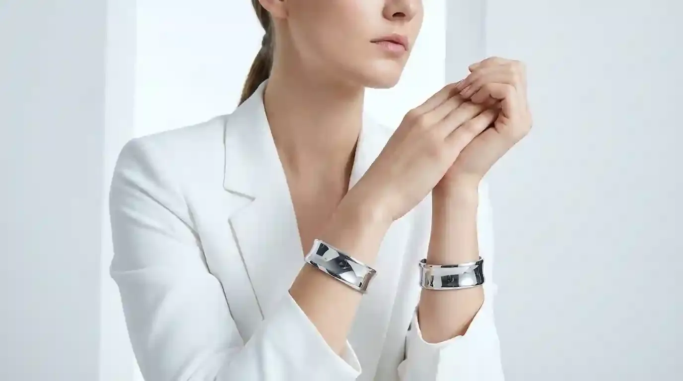 A high-fashion editorial shot of a model wearing symmetrical 316L stainless steel cuffs on both wrists, illustrating modern jewelry symmetry.