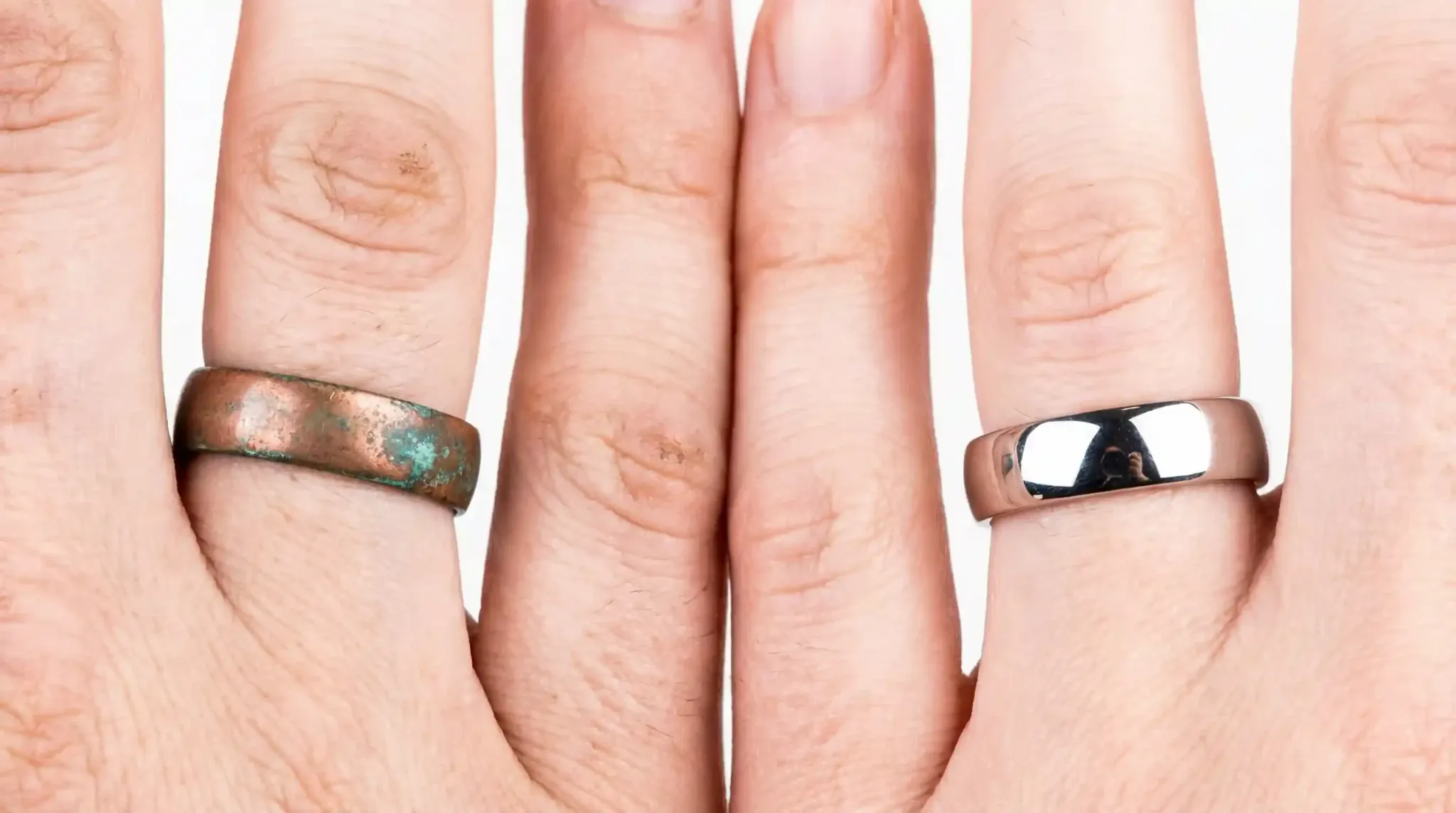 Close-up of a finger showing a green copper oxidation stain next to a clean, polished 316L stainless steel band.