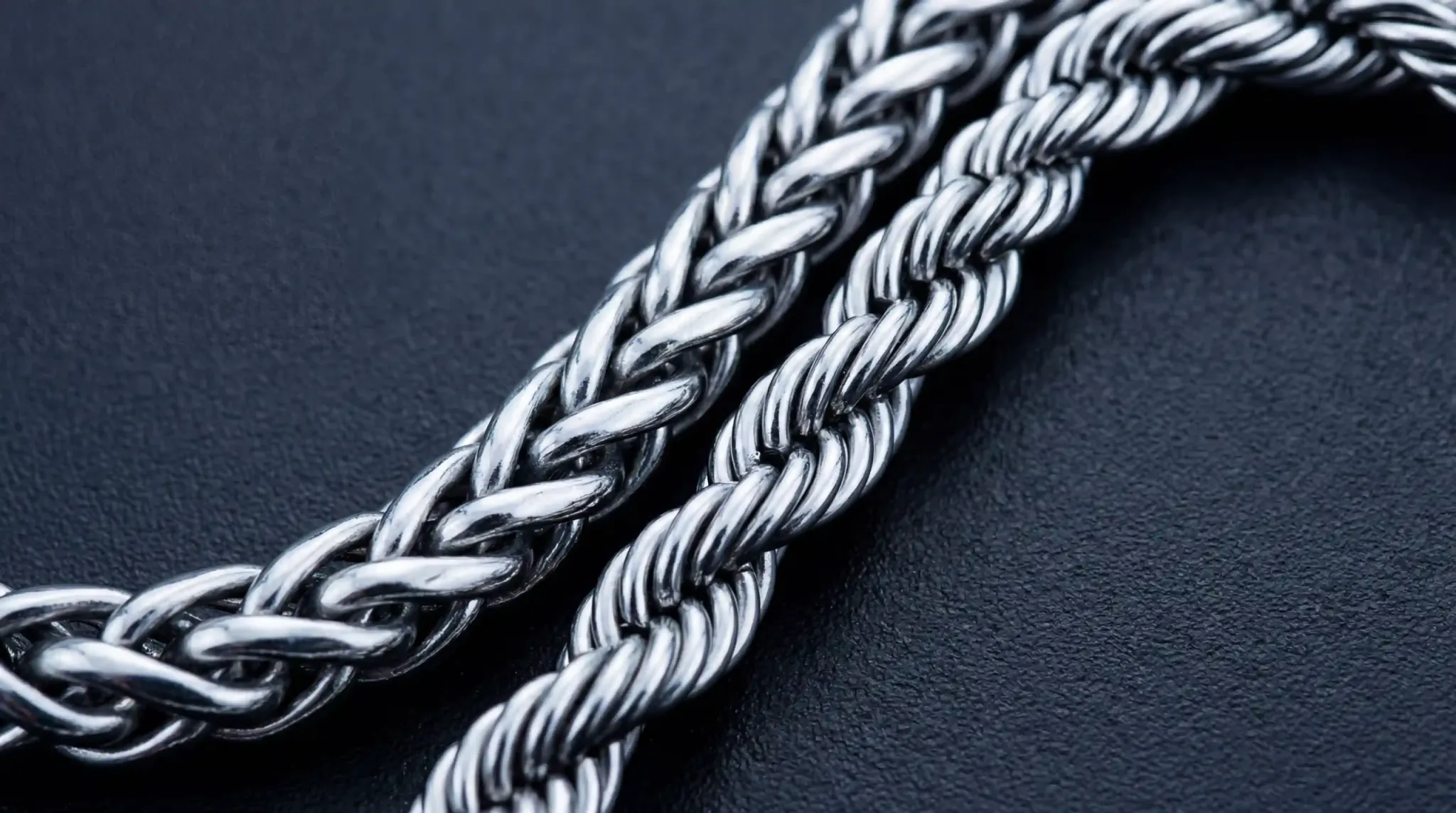 A macro view showing the intricate texture of a 316L stainless steel Wheat chain next to a Rope chain.